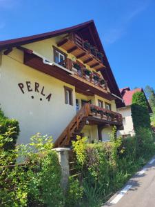a building with a balcony with plants on it at Pensiunea Perla Durau in Durău