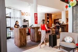 a woman with a suitcase standing at a counter at Ibis Luxembourg Airport in Luxembourg