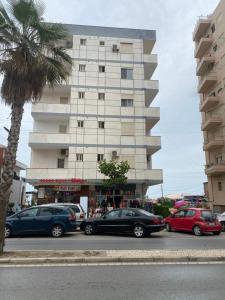 a parking lot with cars parked in front of a building at Roy Apartments in Durrës