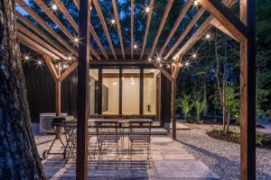 a pergola with a table and chairs under it at 森の宿り 土庵まるやま in Nasu