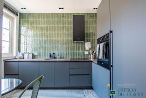 a kitchen with blue cabinets and green tiles at L'Attico del Corso in Trieste