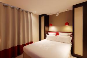 a bedroom with a bed with red and white pillows at Hotel Eden in Paris