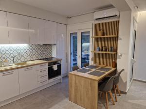 a kitchen with white cabinets and a table and chairs at Cozy Apartment in Asprovalta