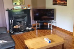 a living room with a television and a fireplace at ocean fields view in Ahnagh Cross