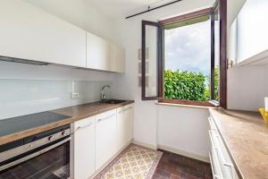 une cuisine avec des armoires blanches et une fenêtre dans l'établissement Villa Verde, à Torri del Benaco