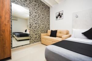 a bedroom with a bed and a couch and a mirror at Naiot Hotel Boutique in Medellín
