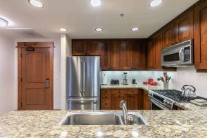 eine Küche mit Holzschränken und einem Edelstahlkühlschrank in der Unterkunft Big Horn Lodge 409 by East West Hospitality in Truckee