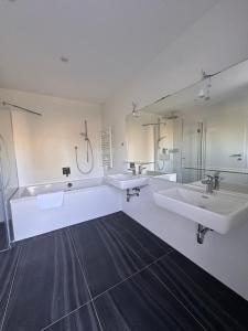 a large bathroom with two sinks and two mirrors at Villa Parndorf Lake 1 next to Outlet in Parndorf +20 photos