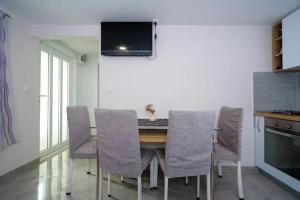 a dining room table with chairs and a tv on the wall at Luna near Split in Kastel Sucurac