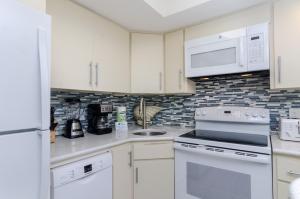 a kitchen with white appliances and white cabinets at Shearin by Bryant Real Estate in Wrightsville Beach