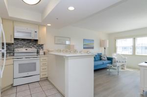 a kitchen and living room with a blue couch at Shearin by Bryant Real Estate in Wrightsville Beach