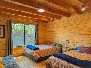 a bedroom with two beds in a log cabin at Cabaña Ohana in Mesa de las Tablas