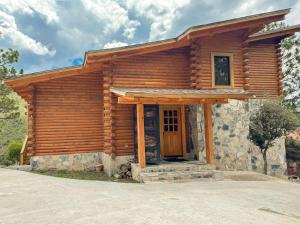 a log cabin with a wooden door and a porch at Cabaña Ohana in Mesa de las Tablas