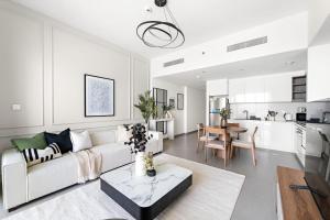 un soggiorno bianco con divano bianco e tavolo di Silkhaus Elegant 1BDR in Downtown Views II a Dubai