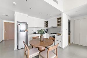 una cucina bianca con tavolo e sedie in legno di Silkhaus Elegant 1BDR in Downtown Views II a Dubai