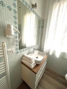 a white bathroom with a sink and a mirror at Airoldi Palace Apartment in Chioggia