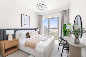 una camera da letto bianca con un letto grande e una scrivania di Silkhaus Elegant 1BDR in Downtown Views II a Dubai