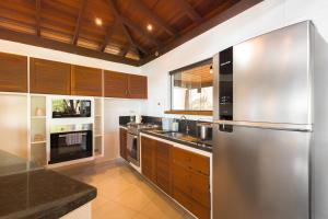 Una cocina con electrodomésticos de acero inoxidable y gabinetes de madera. en Eco Baepi Residence, en Ilhabela 225 fotos más