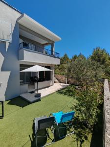 a view of a house with a lawn and an umbrella at Olive Tree Apartment Zečevo in Rogoznica
