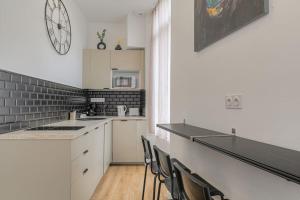 una cocina con encimeras blancas y un reloj en la pared en Selva, appartement cozy, Lyon 8ème, en Lyon