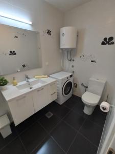 a bathroom with a toilet sink and a washing machine at Olive Tree Apartment Zečevo in Rogoznica