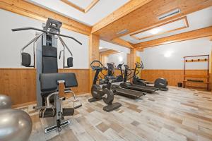 a gym with several treadmills and exercise bikes at Aparthotel Princess in Canazei