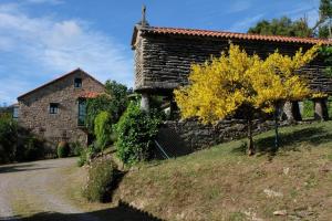 a stone house with a tree in front of it at Fogar dos Antigos in Mazaricos