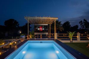 a swimming pool in front of a tv at night at Kynthia Hotel - Adults Only in Kalogria