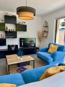 a living room with a blue couch and a tv at Les Dunes, Maison proche plage in Saint-Lunaire