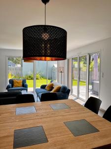 a living room with a dining room table and a large chandelier at Les Dunes, Maison proche plage in Saint-Lunaire