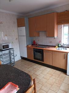 a kitchen with wooden cabinets and a white refrigerator at La Casina independiente de Bruno,de dos dormitorios cerca de la playa in Cudillero