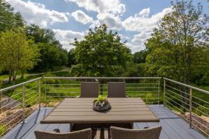 a wooden table and chairs on a deck with trees at Chalet Seeblick I Terrasse I Aussicht I Wandern in Hillesheim