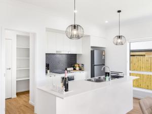 eine weiße Küche mit Spüle und Kühlschrank in der Unterkunft Brand New Comfy Home 4Bedroom designer furniture in Springfield Lakes