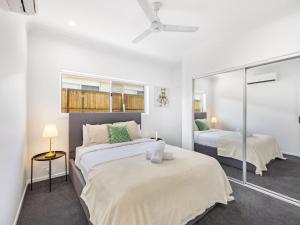 ein weißes Schlafzimmer mit zwei Betten und einem Spiegel in der Unterkunft Brand New Comfy Home 4Bedroom designer furniture in Springfield Lakes