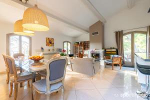 a dining room and living room with a table and chairs at Villa Le Mas des Roches à 15mn airport Marseille in Velaux +24 photos