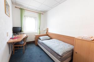 a room with a bed and a desk with a computer at Pension Greiser in Leipzig +41 photos
