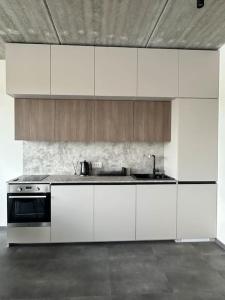 a kitchen with white cabinets and a stove at River Apartments Nemunaiciai in Kaunas