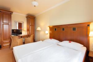 a bedroom with a large white bed with a wooden headboard at Vju Hotel Rügen in Göhren