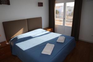a bedroom with a blue bed with two towels on it at Exclusive new apartment in Tavira in Tavira