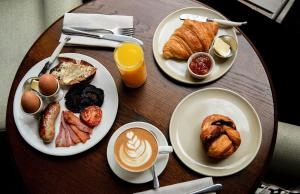 a table with plates of breakfast foods and a cup of coffee at The Hoxton, Holborn in London