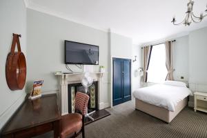a bedroom with a bed and a tv and a fireplace at White Hart, Newmarket by Marston's Inns in Newmarket