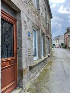 an old brick building with a wooden door on a street at Gite - Val Couesnon in Saint-Ouen-de-la-Rouërie