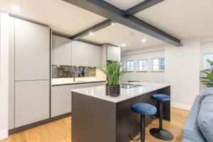 a kitchen with white cabinets and a island with stools at Dragon Suites - Yukina Suite - 2 bed city centre house with garden in Edinburgh