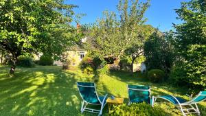 a yard with three chairs and a table in the grass at Sous la glycine in Sarrazac