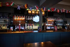 a bar with a lot of alcohol and flags at White Hart, Newmarket by Marston's Inns in Newmarket