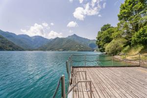 a dock on a lake with mountains in the background at Villa Ledro with Private Dock - Sauna - Hot Tub in Molina di Ledro
