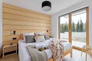 ein Schlafzimmer mit einem Bett mit einer Holzwand in der Unterkunft Golden Apartments Zakopane - Mountain View in Zakopane