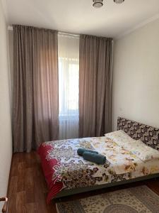a bedroom with a bed with a blanket on it at 3х комнатная посуточно in Taraz