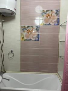 a bathroom with a tub and a shower with flowers on the wall at 3х комнатная посуточно in Taraz +2 photos