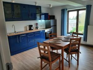 a kitchen with blue cabinets and a table and chairs at Le sommet du Condroz in Ciney